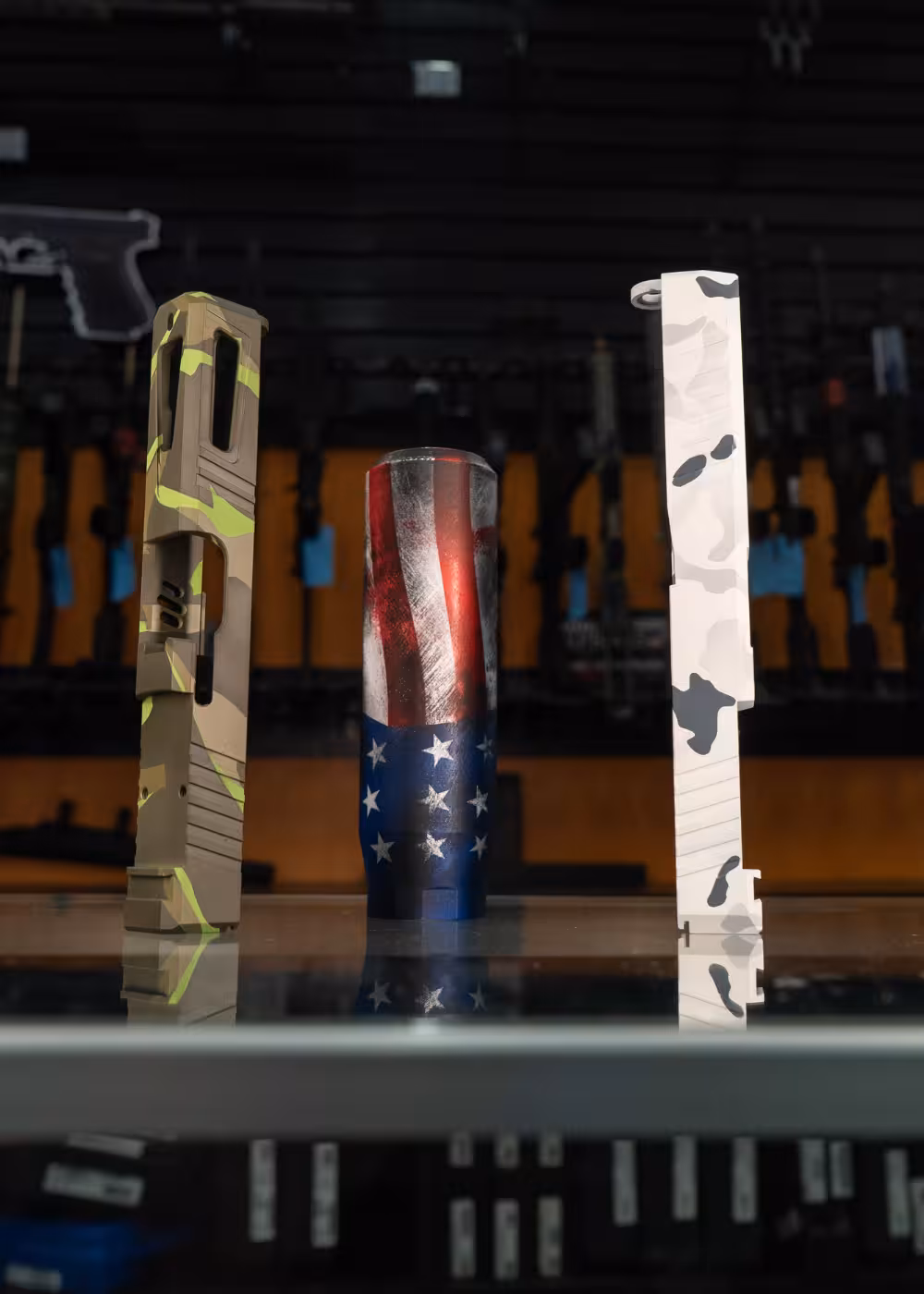 Pistol slides and a suppressor with custom cerakote work done by Tactical Penguin.